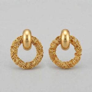 A pair of gold earrings featuring a smooth rounded top and a textured wire mesh circular drop, displayed centrally on a clean neutral light grey background