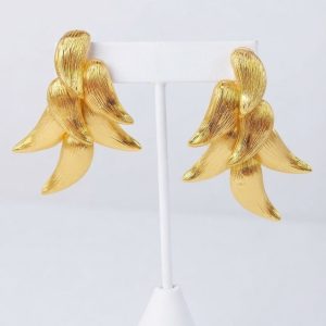 A pair of textured golden cascading leaf earrings displayed professionally on a white T-bar jewelry stand against a clean, neutral light grey background.